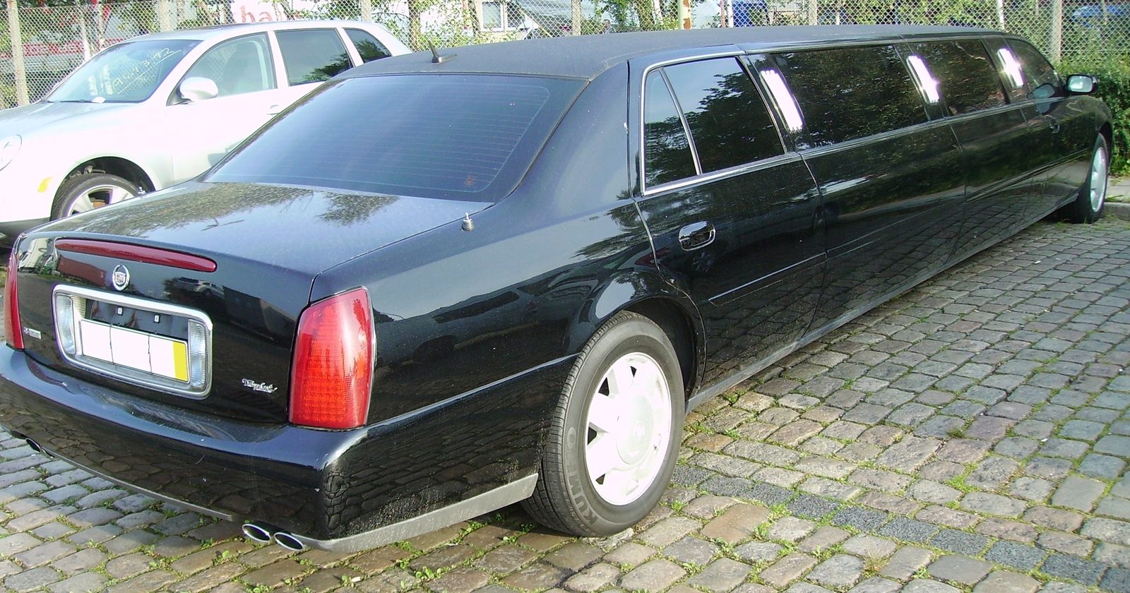 Czarna limuzyna reprezentacyjna (Cadillac DeVille) widziana od tyłu.