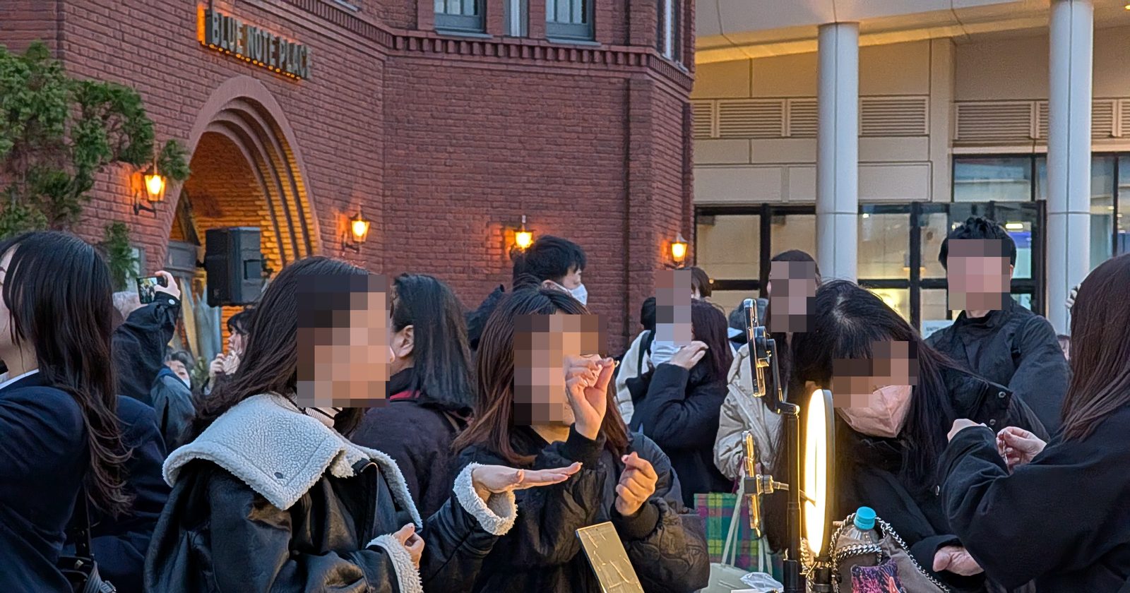 Dłonie trzymające smartfony filmujące pokaz w przestrzeni publicznej — scena promocji w mediach społecznościowych.