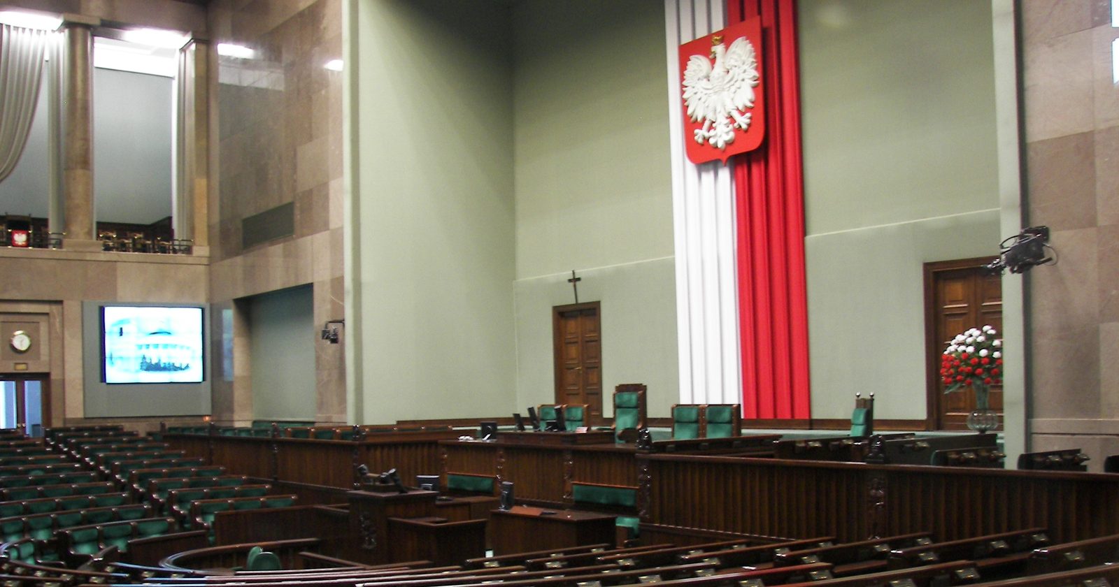 Sala posiedzeń plenarnych Sejmu RP z rzędami ław i foteli poselskich.