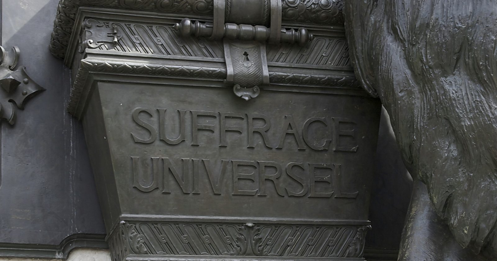 Brązowa urna wyborcza z wyrytym napisem „Suffrage universel” (powszechne prawo wyborcze) na cokole pomnika.